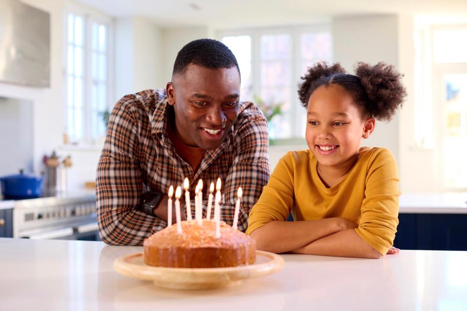 Dad and daughter blowing out birthday candles. 