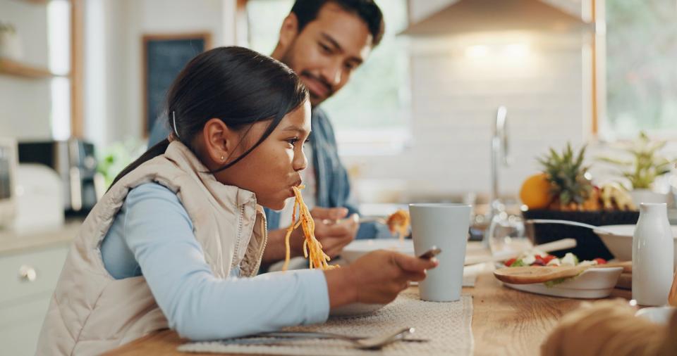 Dad and daughter eating spaghetti. 