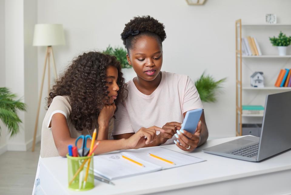 Mom showing her daughter something on her phone.