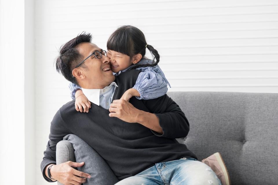 Daughter hugging her dad on couch.