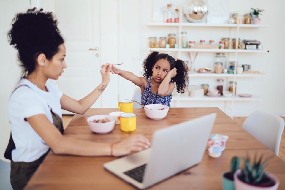 Upset daughter eating breakfast with mom. 