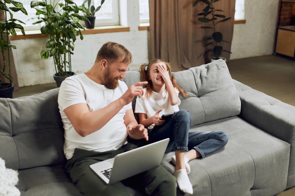 Man and daughter on couch with laptop.