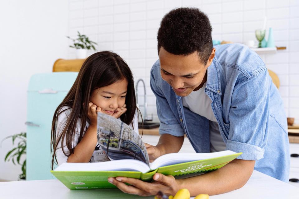 Dad and daughter reading a book.