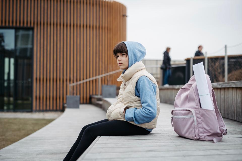 Girl waiting for their parent at school pickup.