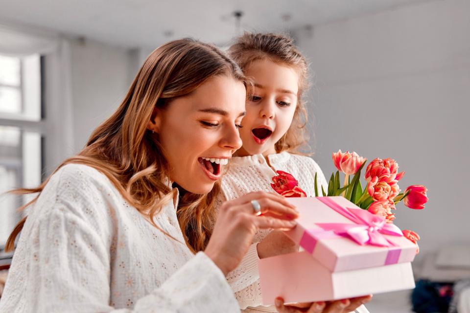Mom and little girl opening a present, smiling.