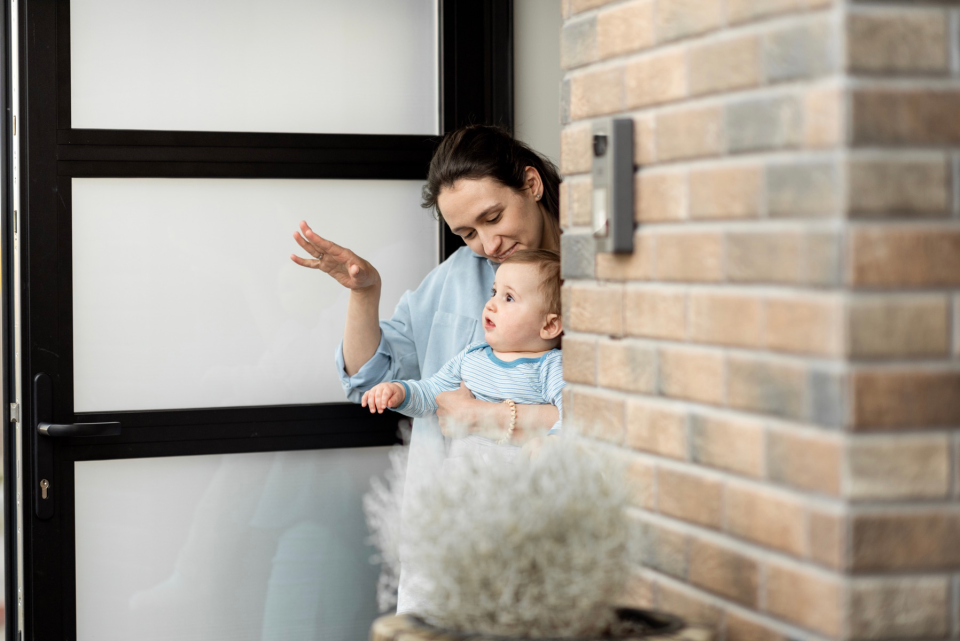 Mom and baby waving goodbye to other parent.