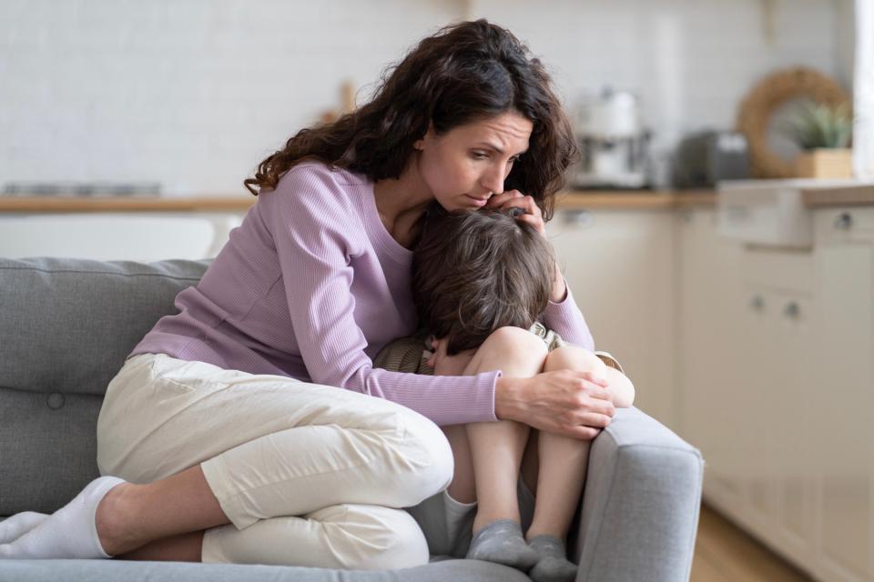 Mom comforting son on the couch.