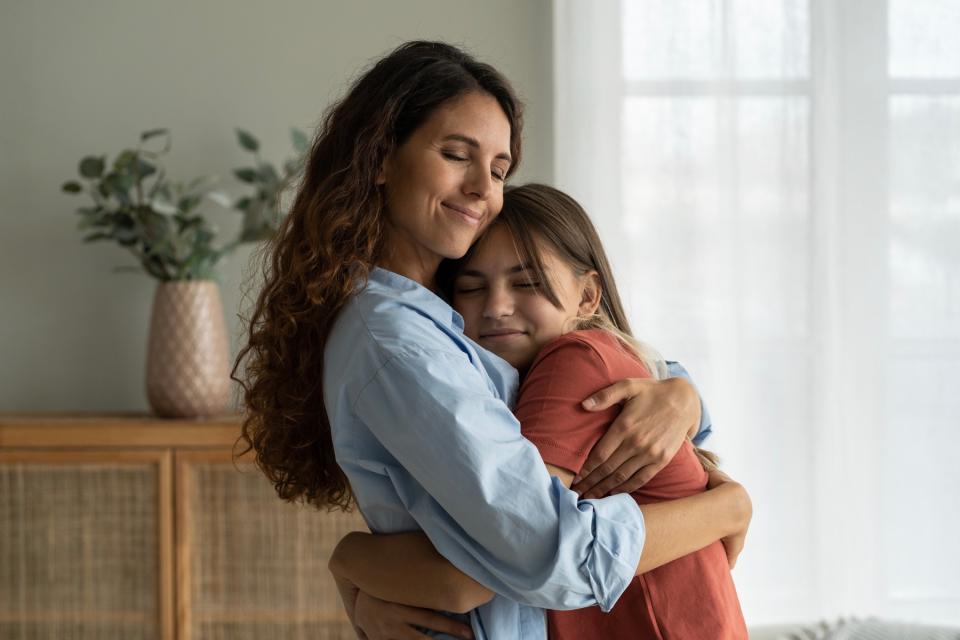 Mom and daughter hugging at home. 
