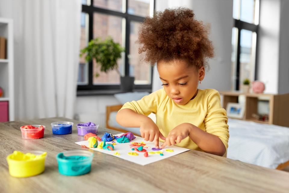 Little girl playing with clay and paint. 