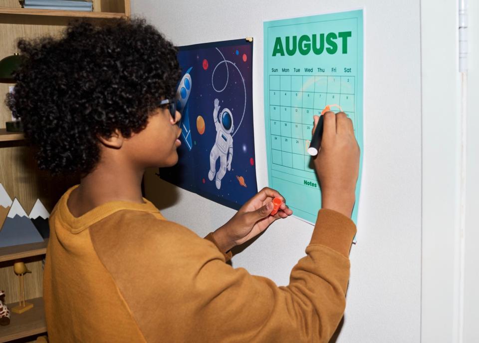 Teen boy updating his wall calendar.