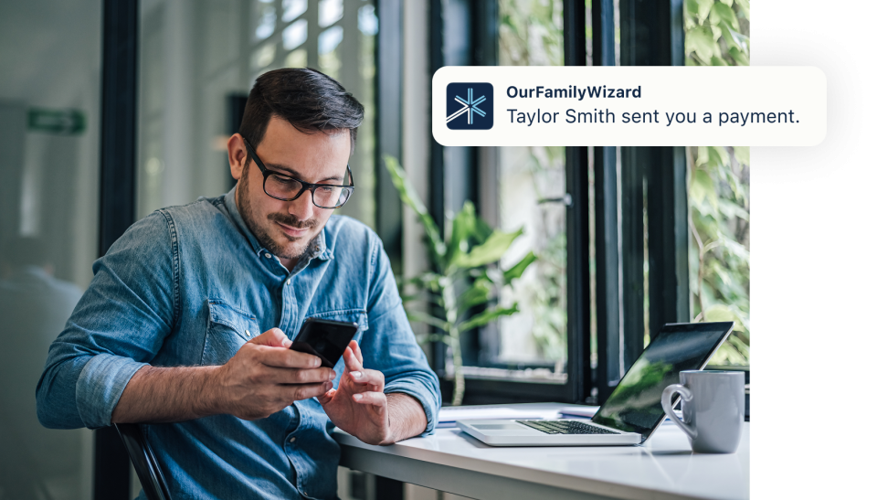 Man looking at phone and seeing notification that he has received a payment in OurFamilyWizard.