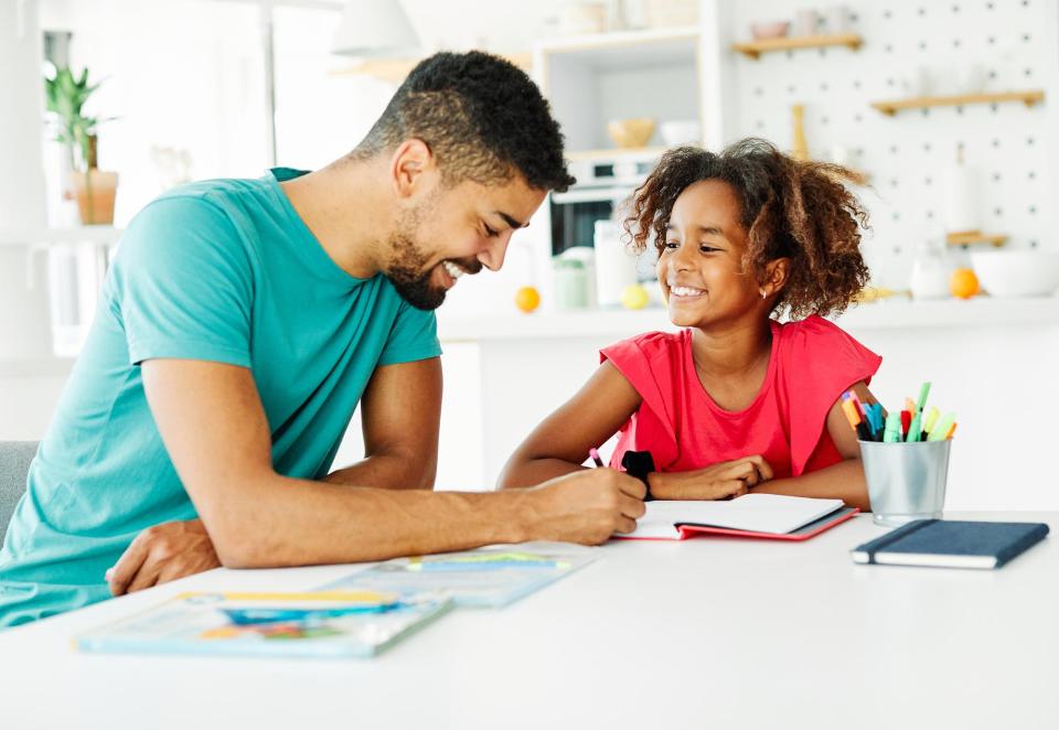 Father helping his daughter with homework at home