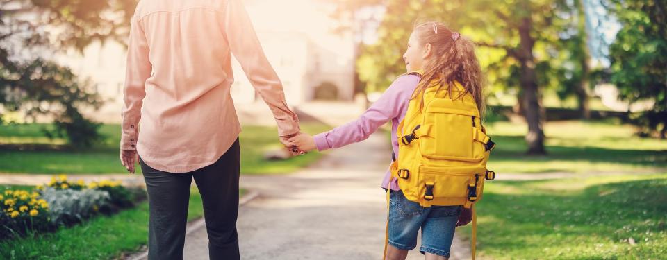 Mother holding her daughter's hand as they walk to school