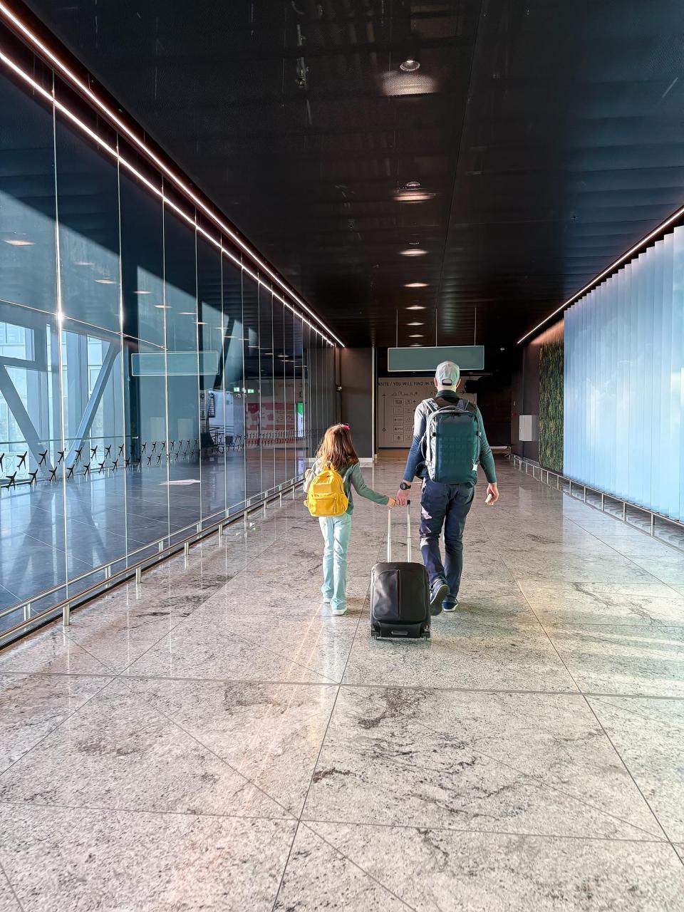 Parent and child with luggage walking toward a boarding gate