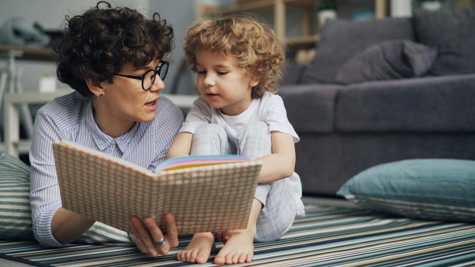 Parent and young child reading a picture book together at home