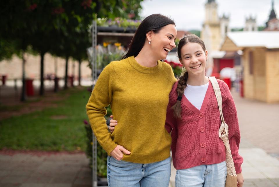 Mom and daughter walking side by side with their arms around each other