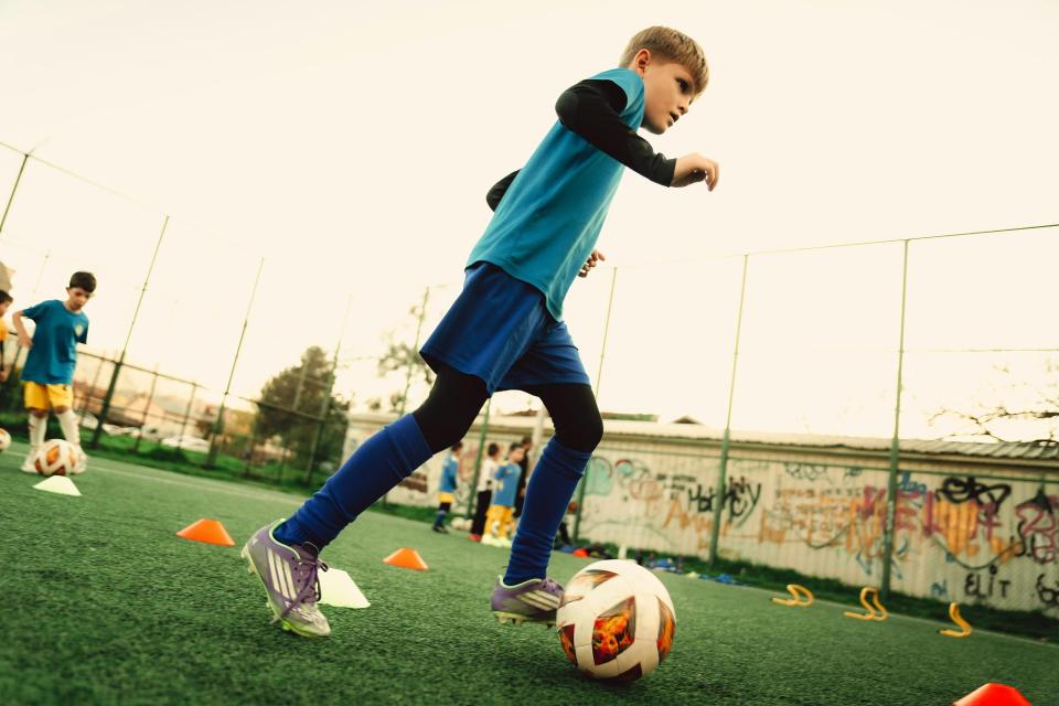 Boy dribbling a soccer ball at practice