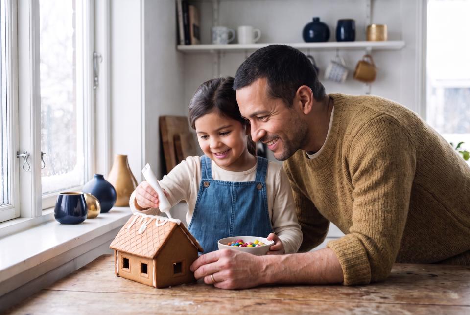 Father and daughter decorating a gingerbread house