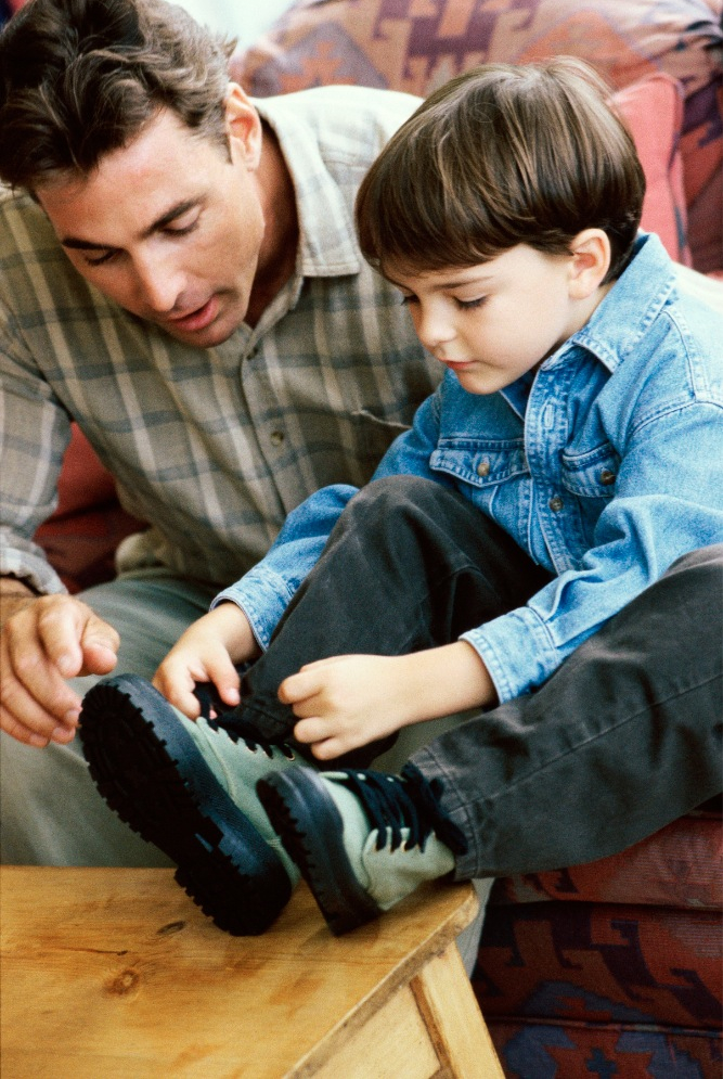Dad teaching son how to tie shoes